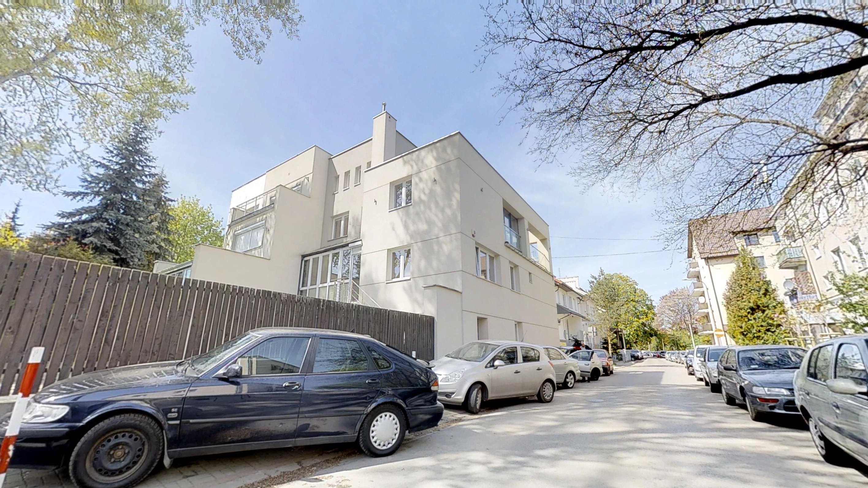Budynek Wąchocka Tower przy ulicy z zaparkowanymi samochodami i drzewami